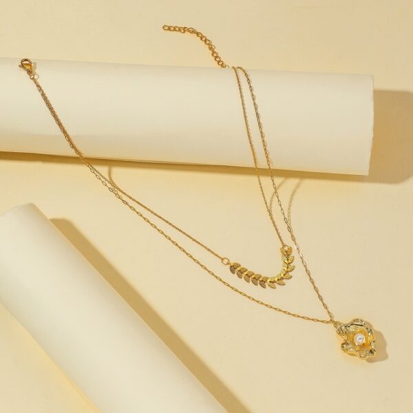Gold-plated layered necklace with a geometric leaf chain and a shell pendant with pearl accent for a stylish and elegant look.