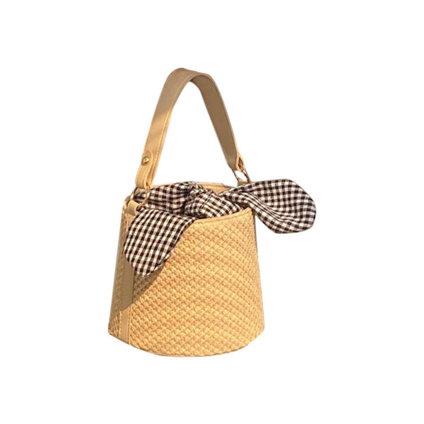Women’s stylish bucket straw bag with a gingham fabric bow, perfect for summer fashion and casual outings.