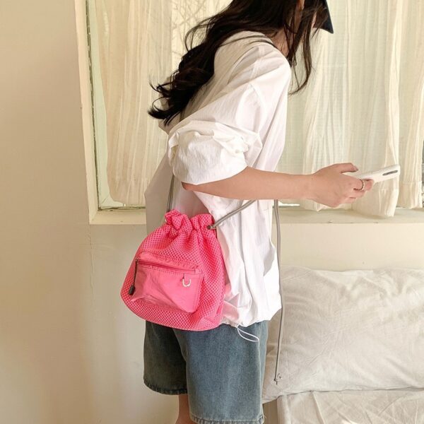 Trendy small mesh drawstring bucket bag with adjustable shoulder strap and front zip pocket, perfect for casual wear.