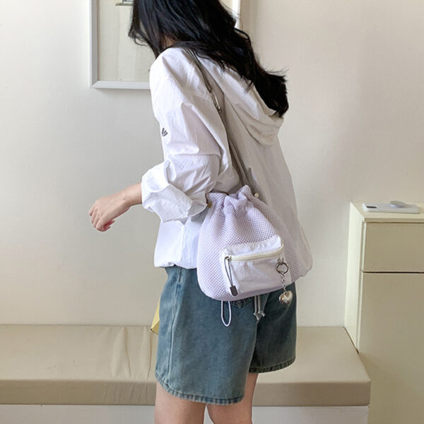 Trendy small mesh drawstring bucket bag with adjustable shoulder strap and front zip pocket, perfect for casual wear.
