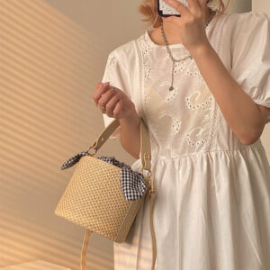 Women’s stylish bucket straw bag with a gingham fabric bow, perfect for summer fashion and casual outings.