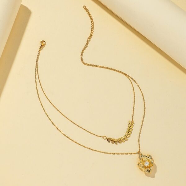 Gold-plated layered necklace with a geometric leaf chain and a shell pendant with pearl accent for a stylish and elegant look.